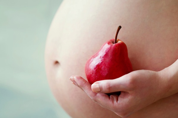 Pregnant woman belly and red pear