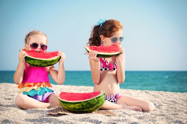 Bambine mangiano anguria sulla spiaggia