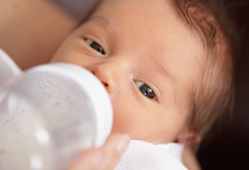 Mother bottle feeding her baby boy